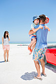 Father hugging children on beach