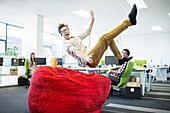 Businessman jumping into beanbag chair
