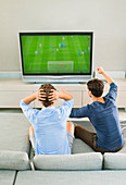 Men watching soccer game on sofa