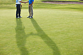 Senior men shaking hands on golf course