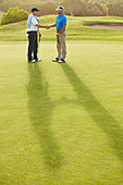 Senior men shaking hands on golf course