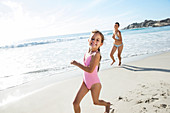 Mother and daughter running on beach