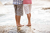 Senior couple standing on rock at beach