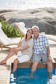 Older couple relaxing by swimming pool