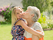 Older woman kissing granddaughter