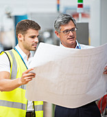 Workers viewing blueprints in factory