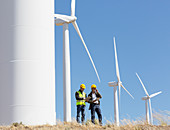 Workers talking by wind turbines