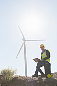 Worker using laptop by wind turbine