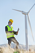 Worker using laptop by wind turbine