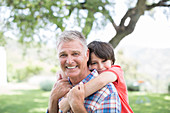 Man piggybacking grandson outdoors