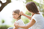 Mother fixing daughter's hair outdoors