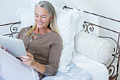 Senior woman using digital tablet on bed