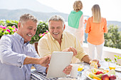Senior men using tablet at patio table