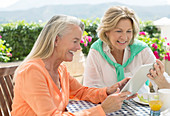 Senior women using tablet at patio table