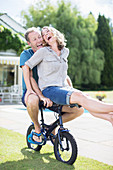 Couple riding small bicycle in grass