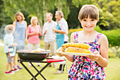 Smiling girl holding grilled corn