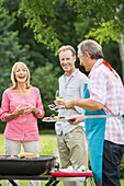 Family standing at barbecue in backyard