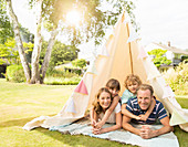 Family relaxing in teepee in backyard