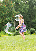 Girl playing with bubbles in backyard