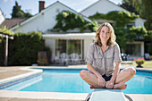 Woman sitting on diving board at poolside