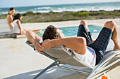 Man relaxing in lounge chair at poolside