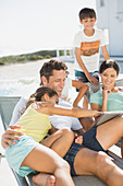 Family using tablet on lounge chairs side