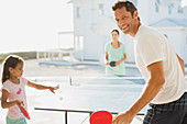 Family playing table tennis outside house