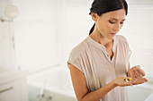 Woman looking at pills in hand