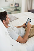 Man using digital tablet on bed