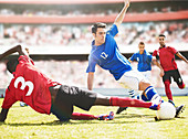 Soccer players kicking ball on field
