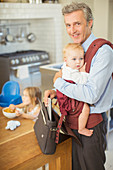 Businessman carrying baby in kitchen