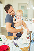 Father holding baby and folding laundry