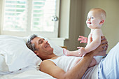 Father playing with baby on bed