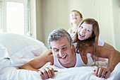 Father and children playing on bed