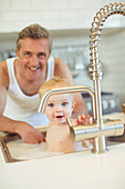 Father bathing baby in kitchen sink