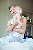 Father holding baby on bed