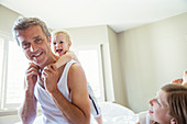 Father and children playing on bed