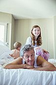 Father playing with children on bed