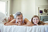 Father and children relaxing on bed