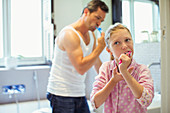Father and daughter brushing teeth