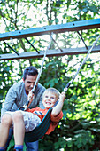 Father pushing son on swing outdoors