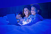 Mother and children using tablet in bed