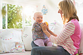 Mother playing with baby girl on sofa