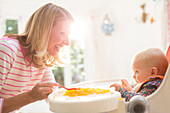 Mother feeding baby girl in high chair