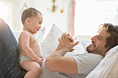 Father playing with baby son on sofa