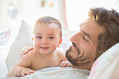 Father and baby boy relaxing on sofa