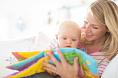 Mother reading to baby girl on sofa