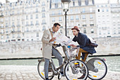 Men on bicycles reading map in Paris