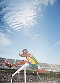 Track and field athlete jumping hurdle