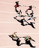 Relay runners handing off batons on track